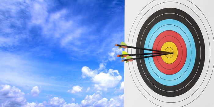 Archery target with arrow over blue sky background