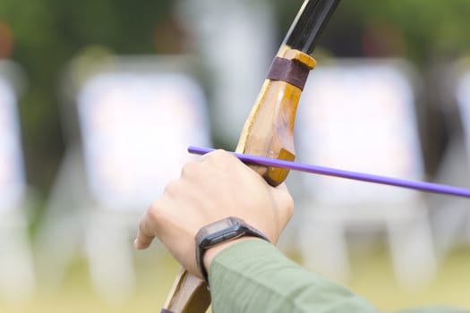 archer holds his bow aiming to the target.