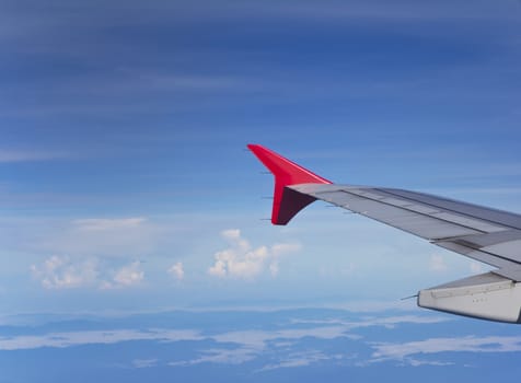 Wing of the plane over blue sky background, view from the window of a plane 