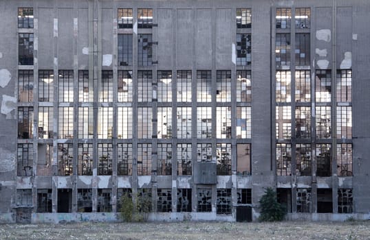 Old abandoned rundown gray facade of glass windows.