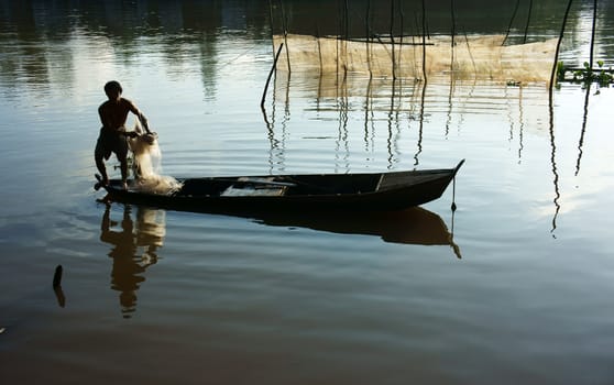Beautiful landcape with reflection of silhouette of fisherman cast a net on river surface water