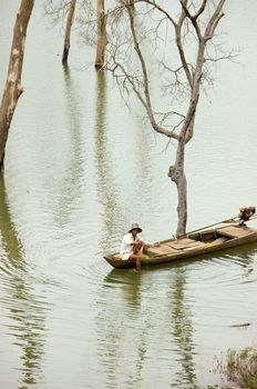  DAK LAK, VIET NAM- SEPTEMBER 3: Fisherman net fish on lake, many dry tree on the lake in Dak Lak, Viet Nam on September 3, 2013     