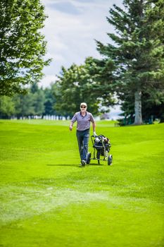 Mature Golfer on a Golf Course Walking with Golf bag