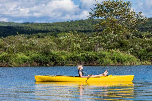 Calm River and Woman relaxing in a Yellow Kayak