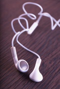 White earphones over a dark wooden background