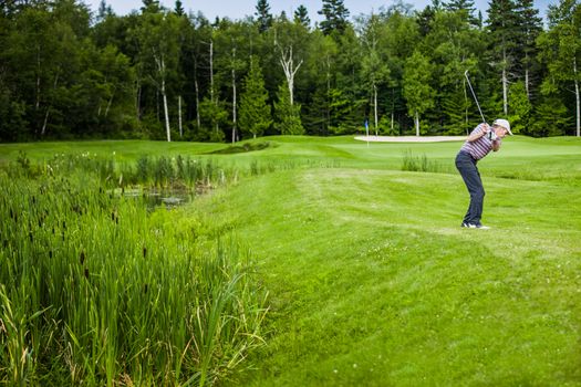 Mature Golfer on a Golf Course Taking a Swing in the Fairway (approch shot)