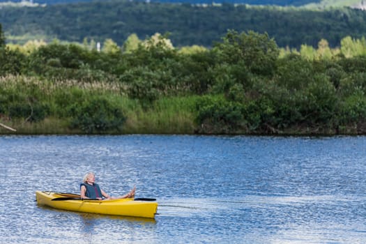 Calm River and Woman relaxing in a Yellow Kayak