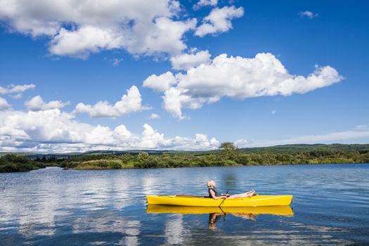 Calm River and Woman relaxing in a Yellow Kayak