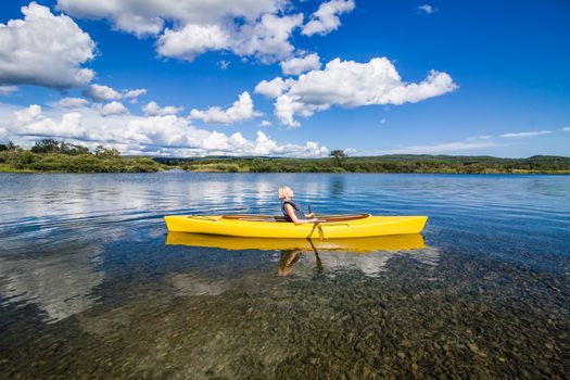 Calm River and Woman relaxing in a Yellow Kayak