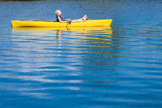 Calm River and Woman relaxing in a Yellow Kayak