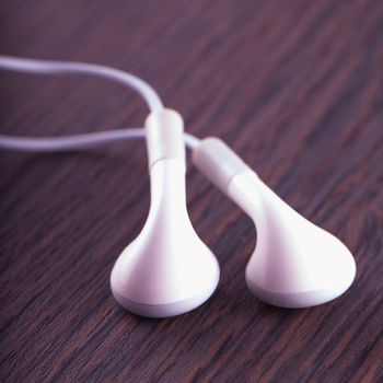 White earphones over a dark wooden background