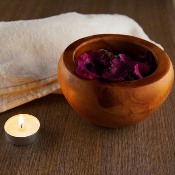 Pot pourri in wooden cup, candle and towel