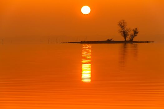 The sun shining through the fog on an early morning on Truman Lake in Missouri.  The fog help slihouette an island on the water.