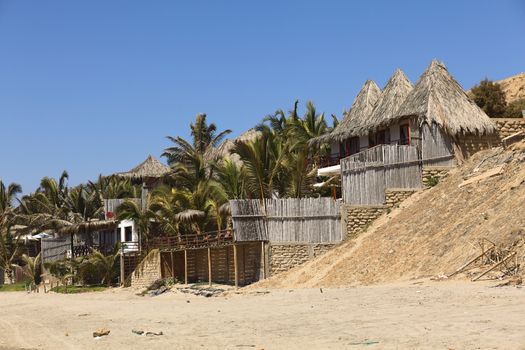 MANCORA, PERU - AUGUST 17, 2013: Thatched roof accomodation with palm trees along the sandy beach on August 17, 2013 in Mancora, Peru. Mancora is one of the most popular beach towns of Peru. 