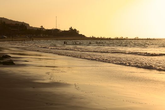 MANCORA, PERU - SEPTEMBER 15, 2013: Unidentified people on the beach and in the water in the light of the setting sun on September 15, 2013 in Mancora, Peru. Mancora is a popular beach town in Northern Peru.  