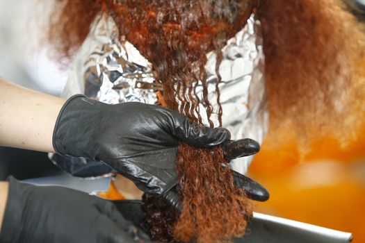 Close-up of the head of a woman in the process of getting her hair dyed by her beautician