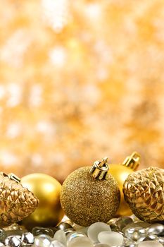 Golden Christmas background with ornaments and pine cones