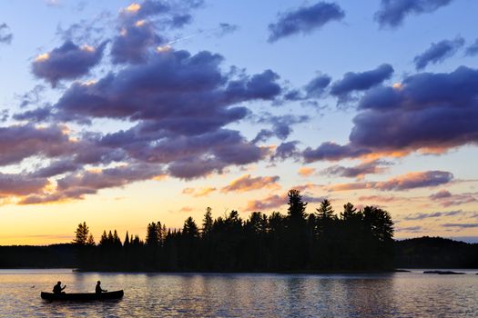 Silhouette of island and canoe on lake at sunset in Algonquin Park, Canada