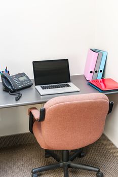 Workstation in office with swivel chair desk and laptop computer