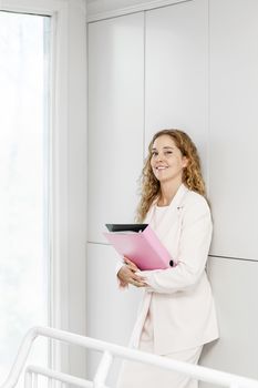 Confident career business woman standing in office hallway holding binder