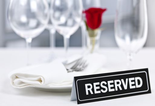 Reserved romantic restaurant table setting with roses plates and cutlery