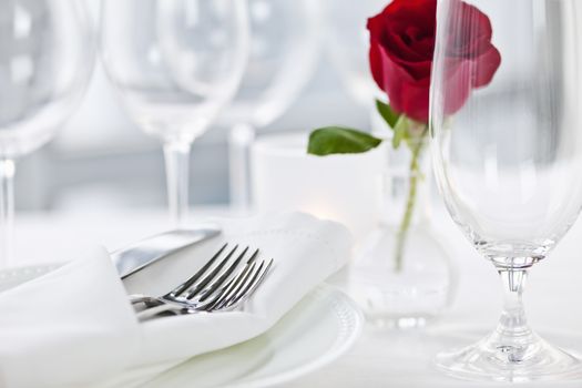 Romantic restaurant table setting with rose candle plates and cutlery