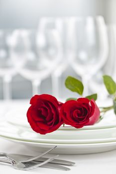 Romantic restaurant table setting for two with roses plates and cutlery