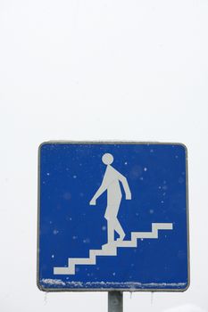 Road sign of a pedestrian underpass in winter with ice