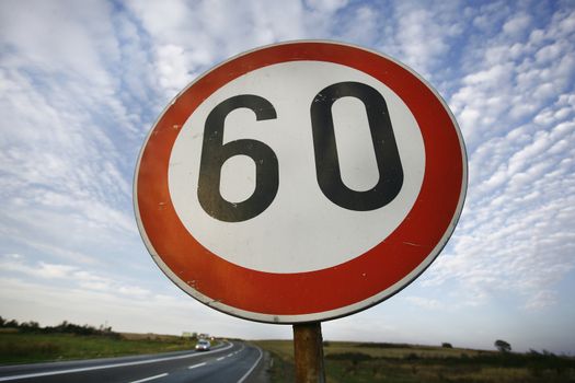 road sign speed limit sixty under cloudy blue sky