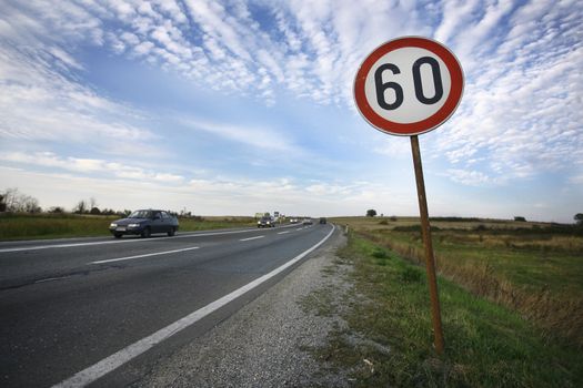 road sign speed limit sixty under cloudy blue sky