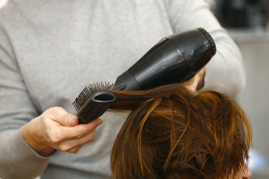 stylist drying woman hair in hairdresser salon