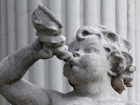 Stone statue of an angel holding a trumpet that blows.