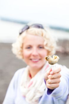 Young Woman Eating a prepared and out of the shell Whelk (bourgot in french)