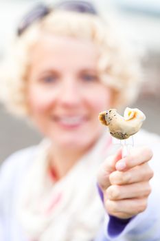 Young Woman Eating a prepared and out of the shell Whelk (bourgot in french)