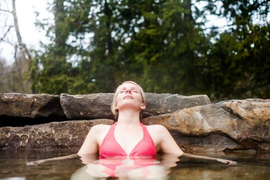 Young Woman Relaxing in a Outdoor Nordic Spa, in the forest.