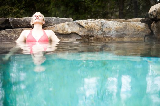 Young Woman Relaxing in a Outdoor Nordic Spa, in the forest.