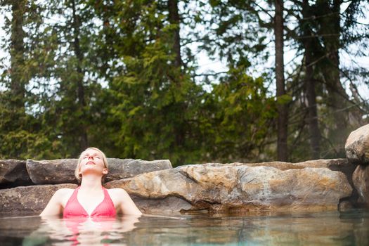 Young Woman Relaxing in a Outdoor Nordic Spa, in the forest.