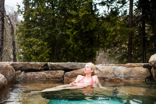 Young Woman Relaxing in a Outdoor Nordic Spa, in the forest.