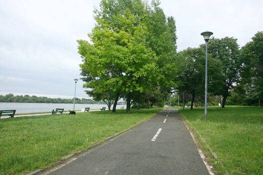 Footpath reached in the trees along the river with benches