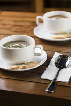 Vertical shot of two cups of mushroom soup ready to be served.