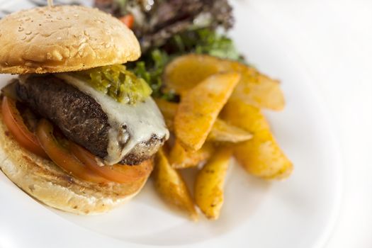 Thick juicy chicken burger with fries isolated on white.