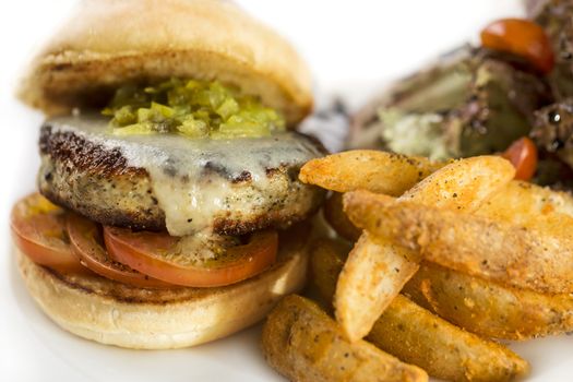 Thick juicy chicken burger with fries isolated on white.