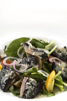 A vetrical shot of a plate of mushroom cooked with cheese and green vegetable.