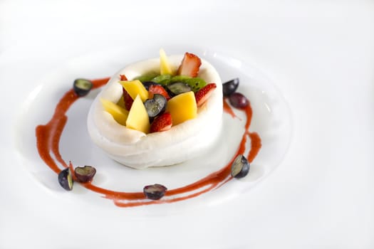 A plate of fruits dessert made of strawberries, raspberry, mango and kiwi wrap in cream isolate on white.