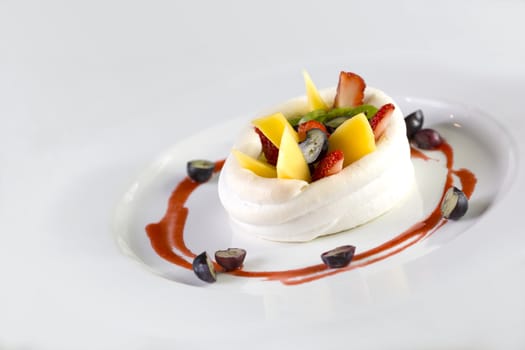 A plate of fruits dessert made of strawberries, raspberry, mango and kiwi wrap in cream isolate on white. 