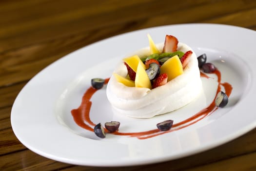 A plate of fruits dessert made of strawberries, raspberry, mango and kiwi wrap in cream. 