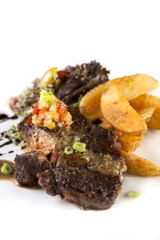 A vertical shot of a plate of thick juicy beef steak to be served with fries and salad on isolated white.