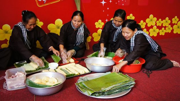 VIET NAM- JAN 15: Group of people with traditional Vietnamese dress (ao ba ba) and bandanna making traditional food- cylindric rice cake ( banh Tet) for Tet ( Lunar New Year) in Vietnam, Jan 15, 2013