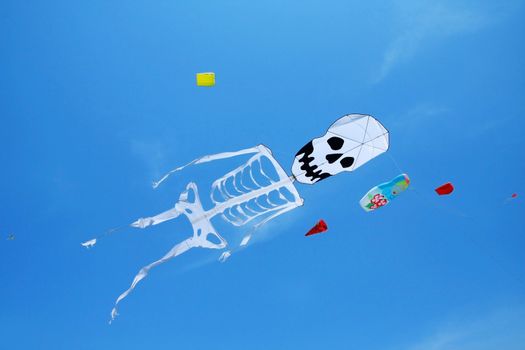 Kite with sketeton's shape flying in the air against blue sky