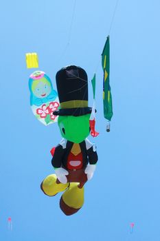 Kite with cartoon character's shape flying in the air against blue sky